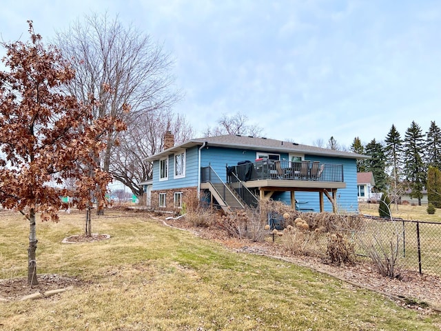 rear view of house with fence, a wooden deck, a chimney, stairs, and a lawn