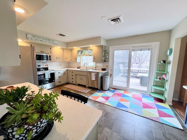 kitchen featuring visible vents, light countertops, decorative backsplash, and appliances with stainless steel finishes