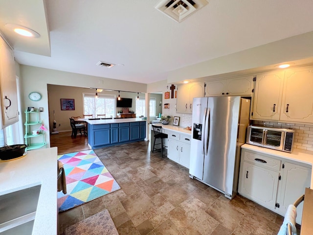 kitchen featuring visible vents, tasteful backsplash, light countertops, and stainless steel fridge