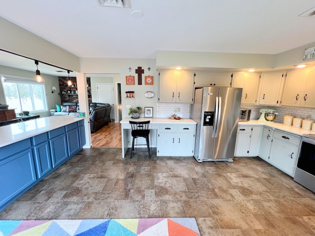 kitchen featuring tasteful backsplash, stove, light countertops, and stainless steel fridge