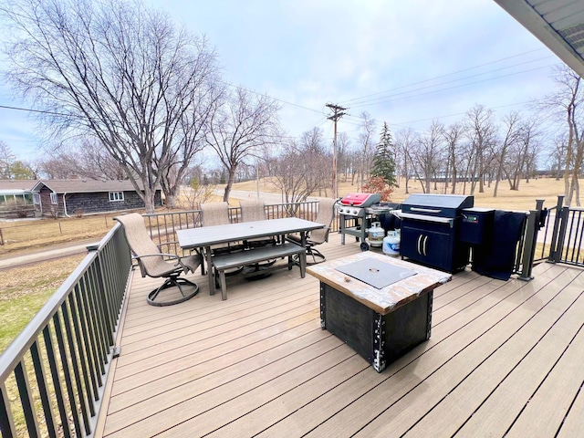 deck featuring outdoor dining area, a fire pit, and area for grilling
