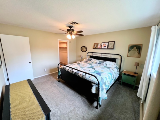 bedroom with a closet, visible vents, carpet, a ceiling fan, and a spacious closet