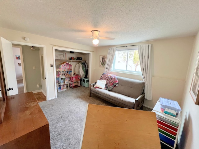 living area with a ceiling fan, carpet floors, and a textured ceiling