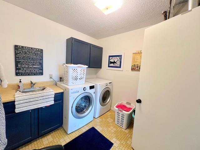 laundry area with washing machine and clothes dryer, cabinet space, a textured ceiling, and a sink