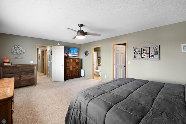 bedroom with a textured ceiling, ensuite bathroom, light carpet, and ceiling fan