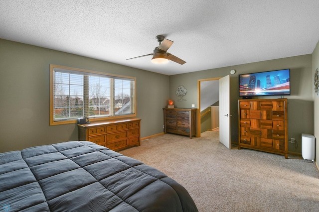 carpeted bedroom featuring a ceiling fan and a textured ceiling