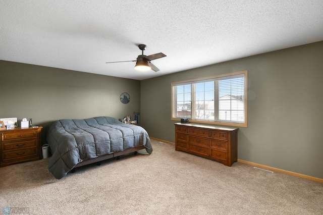 bedroom with baseboards, ceiling fan, a textured ceiling, and light colored carpet