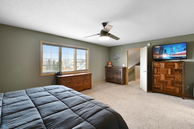 carpeted bedroom with ceiling fan and a textured ceiling