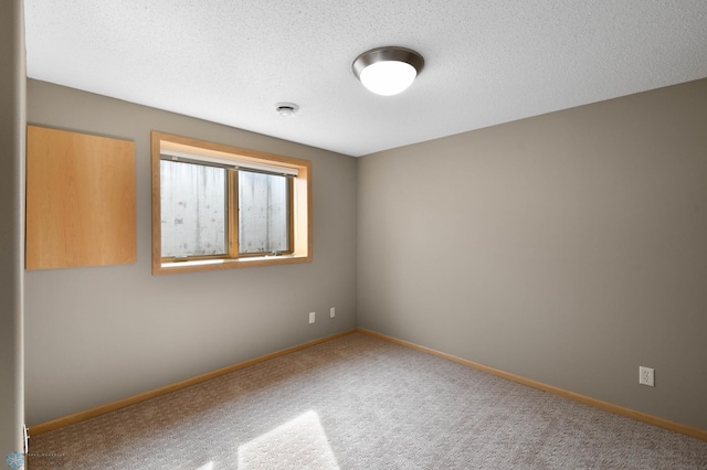 empty room with baseboards, a textured ceiling, and carpet