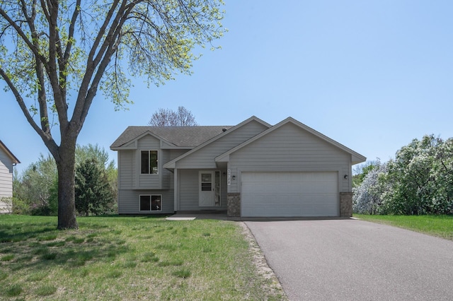 tri-level home with a garage, driveway, and a front lawn