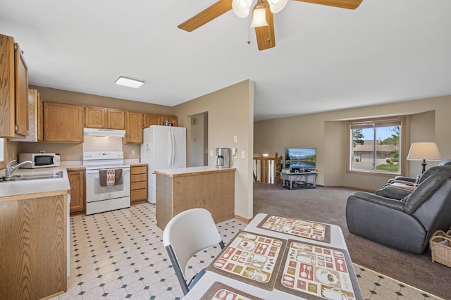 kitchen with white appliances, under cabinet range hood, open floor plan, a sink, and light countertops