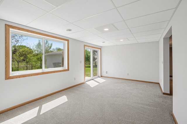 empty room featuring baseboards, carpet floors, and a drop ceiling