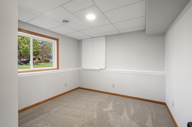 empty room with light carpet, baseboards, and a paneled ceiling