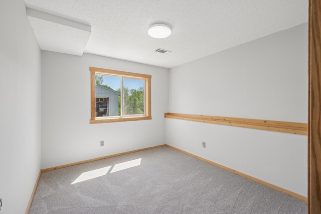 empty room featuring carpet, baseboards, and a textured ceiling