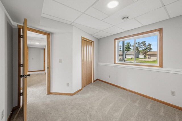 carpeted empty room with a paneled ceiling and baseboards