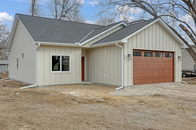 view of front of house featuring dirt driveway, a shingled roof, board and batten siding, and an attached garage