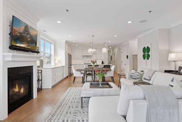 6112 Kellogg Unit 200D, Edina, MN 55424 - living room featuring ornamental molding, light wood finished floors, a glass covered fireplace, recessed lighting, and a chandelier