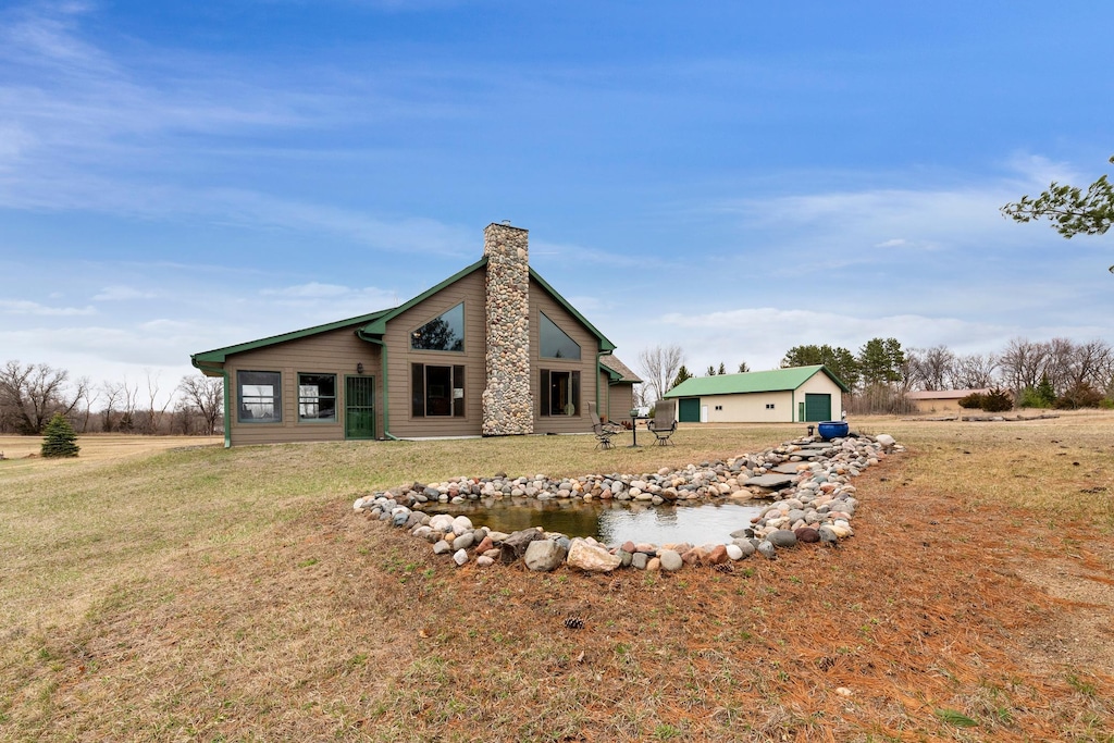 rear view of house featuring a lawn, a chimney, and an outbuilding