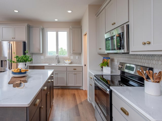 9160 62nd St S, Cottage Grove, MN 55016 - kitchen with appliances with stainless steel finishes, light wood finished floors, recessed lighting, backsplash, and light stone countertops
