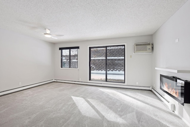 unfurnished living room with a wall mounted air conditioner, ceiling fan, a textured ceiling, carpet floors, and a glass covered fireplace