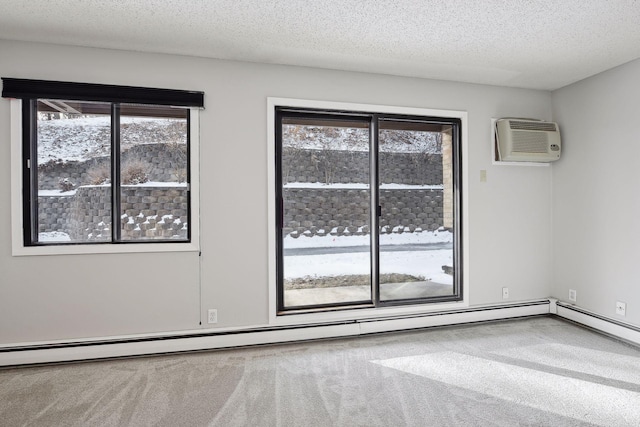 carpeted empty room with plenty of natural light, a wall mounted AC, baseboard heating, and a textured ceiling