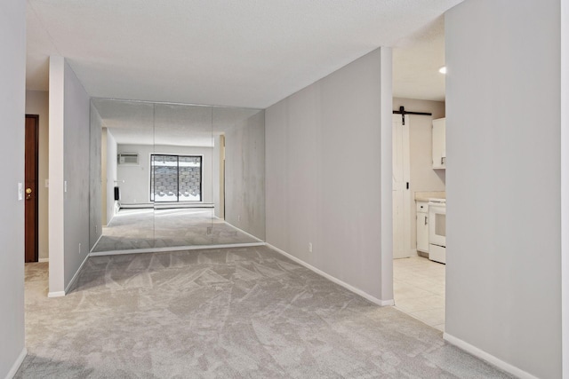 hallway with light carpet, baseboards, an AC wall unit, and a barn door