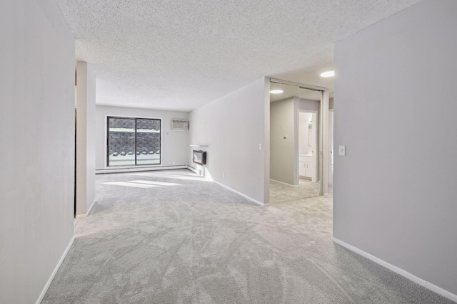 empty room featuring a wall mounted air conditioner, carpet flooring, and a textured ceiling