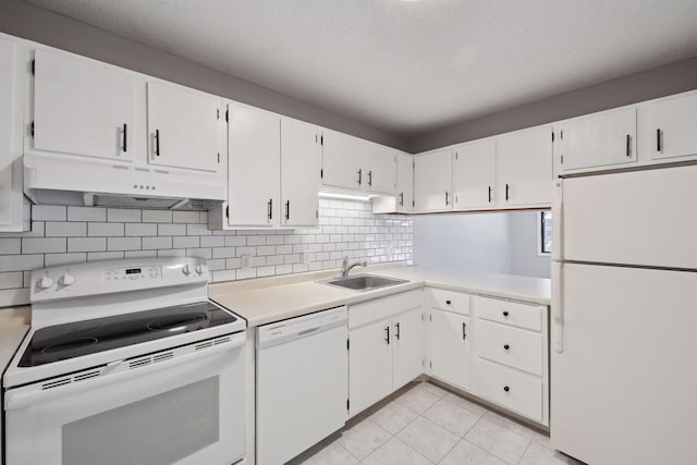 kitchen featuring light countertops, under cabinet range hood, a sink, and white appliances