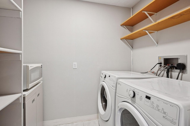 clothes washing area featuring light tile patterned floors, washer and clothes dryer, laundry area, and baseboards