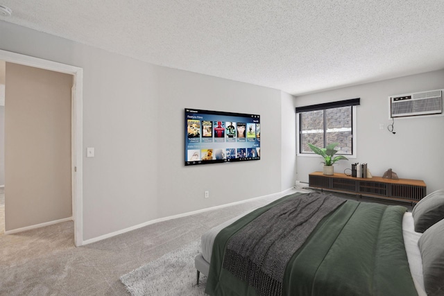 bedroom with a wall mounted AC, a textured ceiling, baseboards, and carpet floors