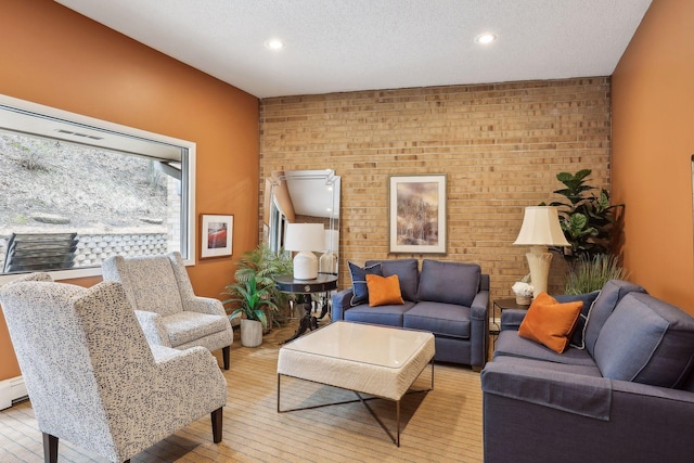 living area with brick wall, recessed lighting, a textured ceiling, and wood finished floors