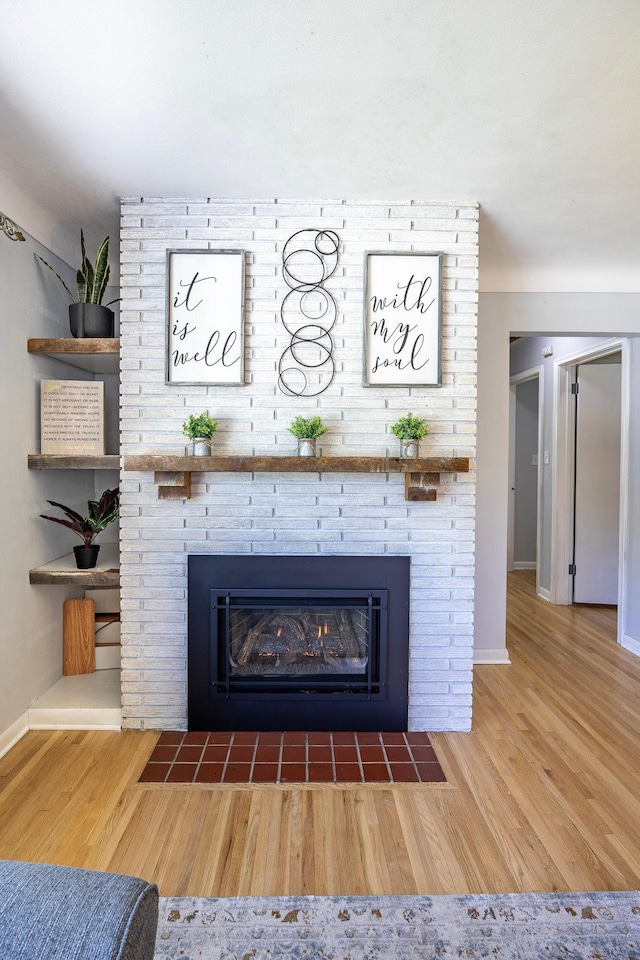 detailed view of a fireplace, wood finished floors, and baseboards