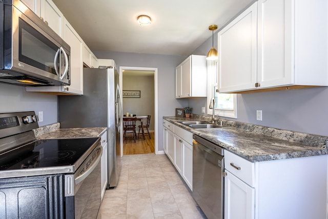 kitchen featuring appliances with stainless steel finishes, a sink, dark countertops, white cabinets, and pendant lighting