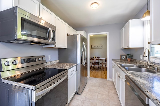 kitchen featuring appliances with stainless steel finishes, a sink, white cabinets, and baseboards