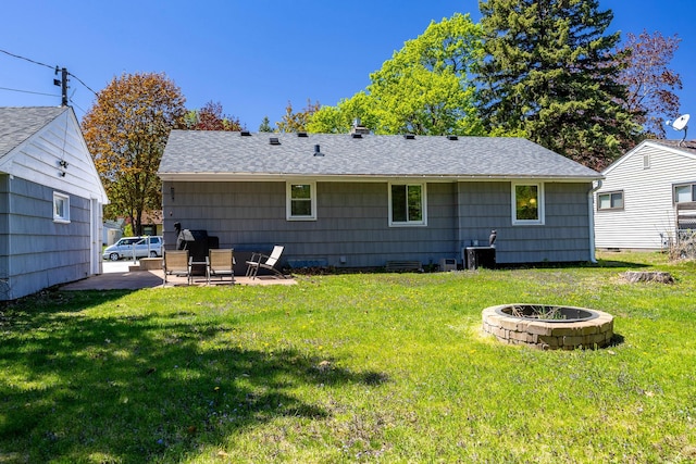 back of house featuring a fire pit, a lawn, and a shingled roof