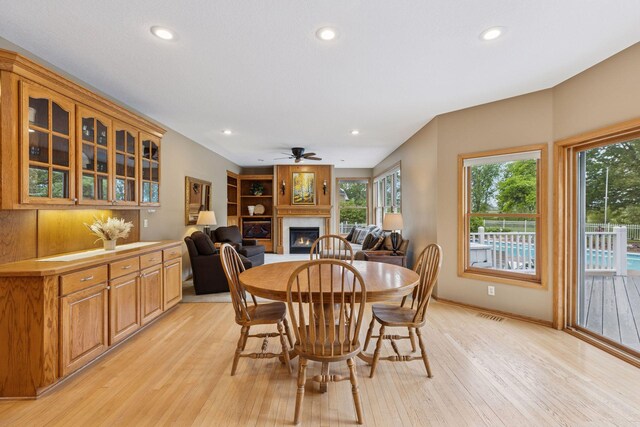 268 Saint Andrews Dr, Hudson, WI 54016 - dining area featuring light wood-style floors, a glass covered fireplace, healthy amount of natural light, a ceiling fan, and recessed lighting
