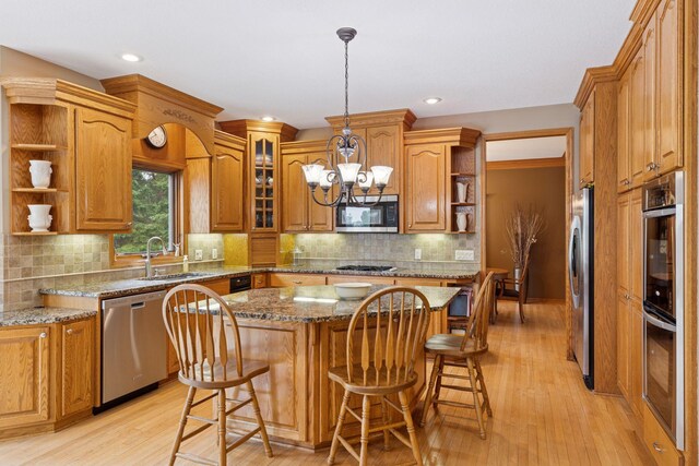 268 Saint Andrews Dr, Hudson, WI 54016 - kitchen with open shelves, stainless steel appliances, a sink, brown cabinets, and a center island
