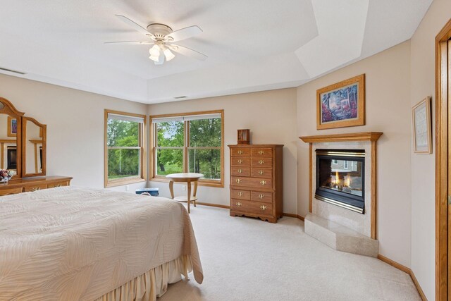 268 Saint Andrews Dr, Hudson, WI 54016 - bedroom featuring a tray ceiling, a multi sided fireplace, light carpet, baseboards, and ceiling fan