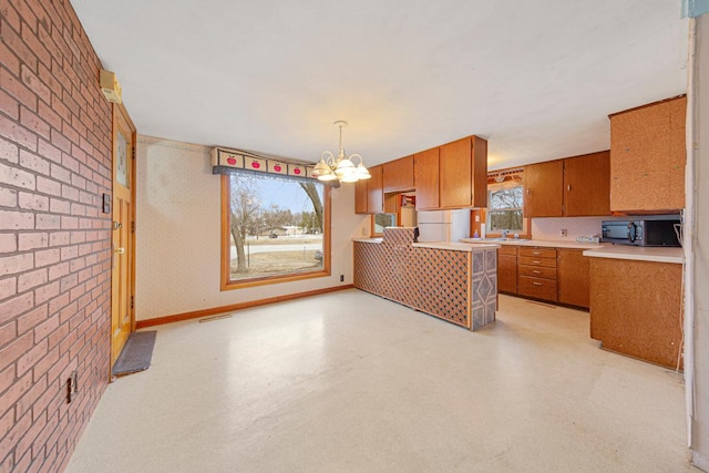 101 State Highway 60 E, Elysian, MN 56028 - kitchen featuring black microwave, brown cabinets, a chandelier, light countertops, and brick wall