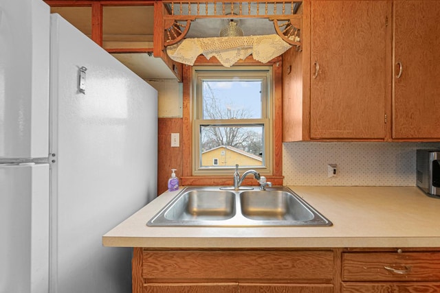 101 State Highway 60 E, Elysian, MN 56028 - kitchen featuring a sink, freestanding refrigerator, light countertops, stainless steel microwave, and brown cabinets