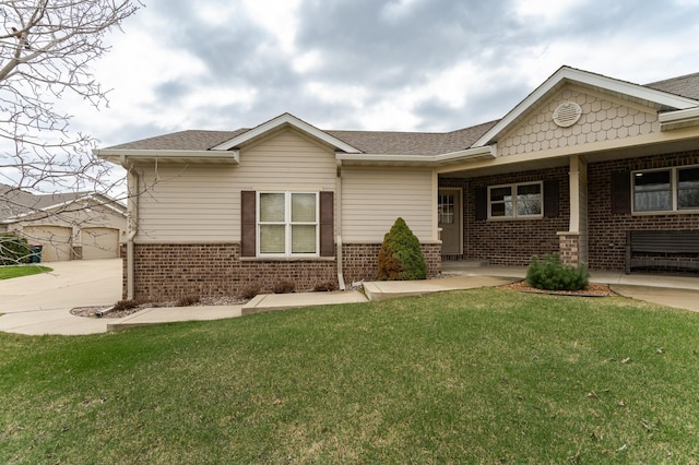 view of front of property featuring brick siding, roof with shingles, and a front lawn