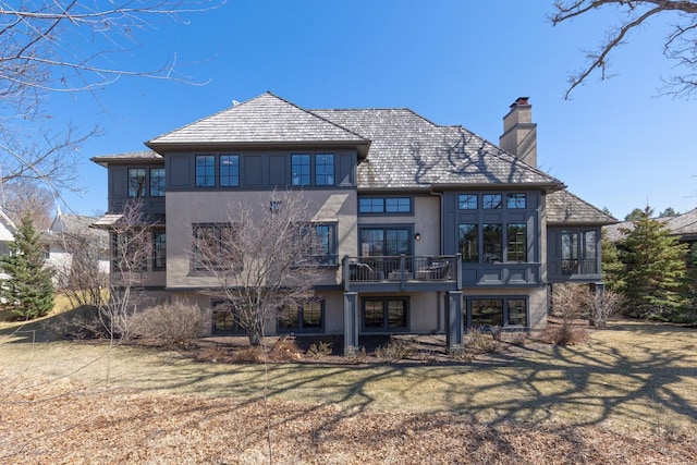 425 Carpenters Pt, Wayzata, MN 55391 - back of house with stucco siding, a chimney, a balcony, and a yard