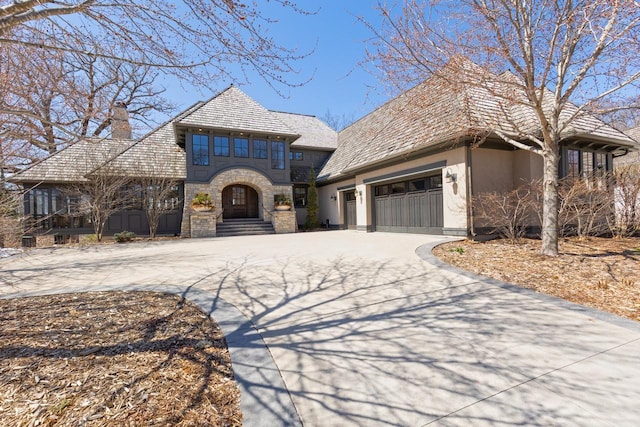 425 Carpenters Pt, Wayzata, MN 55391 - view of front of home with stucco siding, driveway, a chimney, an attached garage, and stone siding