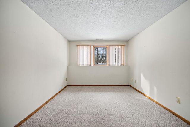 carpeted empty room featuring a textured ceiling and baseboards