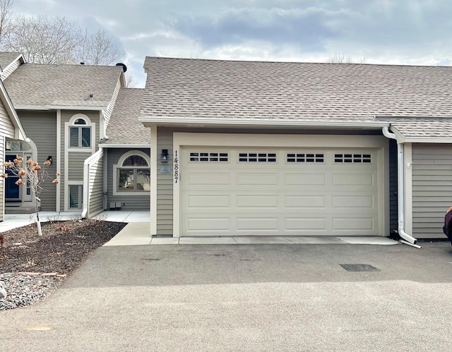 view of front of property featuring an attached garage, a shingled roof, and driveway