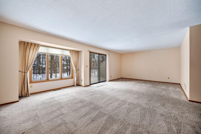 carpeted spare room featuring plenty of natural light, visible vents, and a textured ceiling