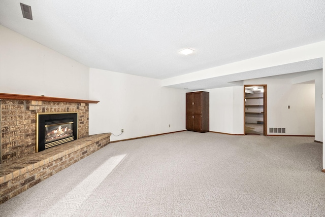 unfurnished living room with a brick fireplace, visible vents, and baseboards