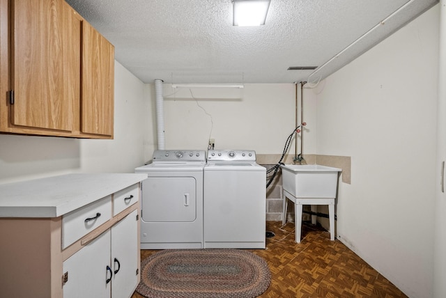 laundry room featuring separate washer and dryer, visible vents, a textured ceiling, and cabinet space