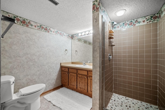 full bathroom featuring a shower stall, a textured ceiling, toilet, and vanity