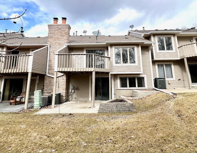 rear view of house with a chimney, a balcony, cooling unit, a patio, and a fire pit